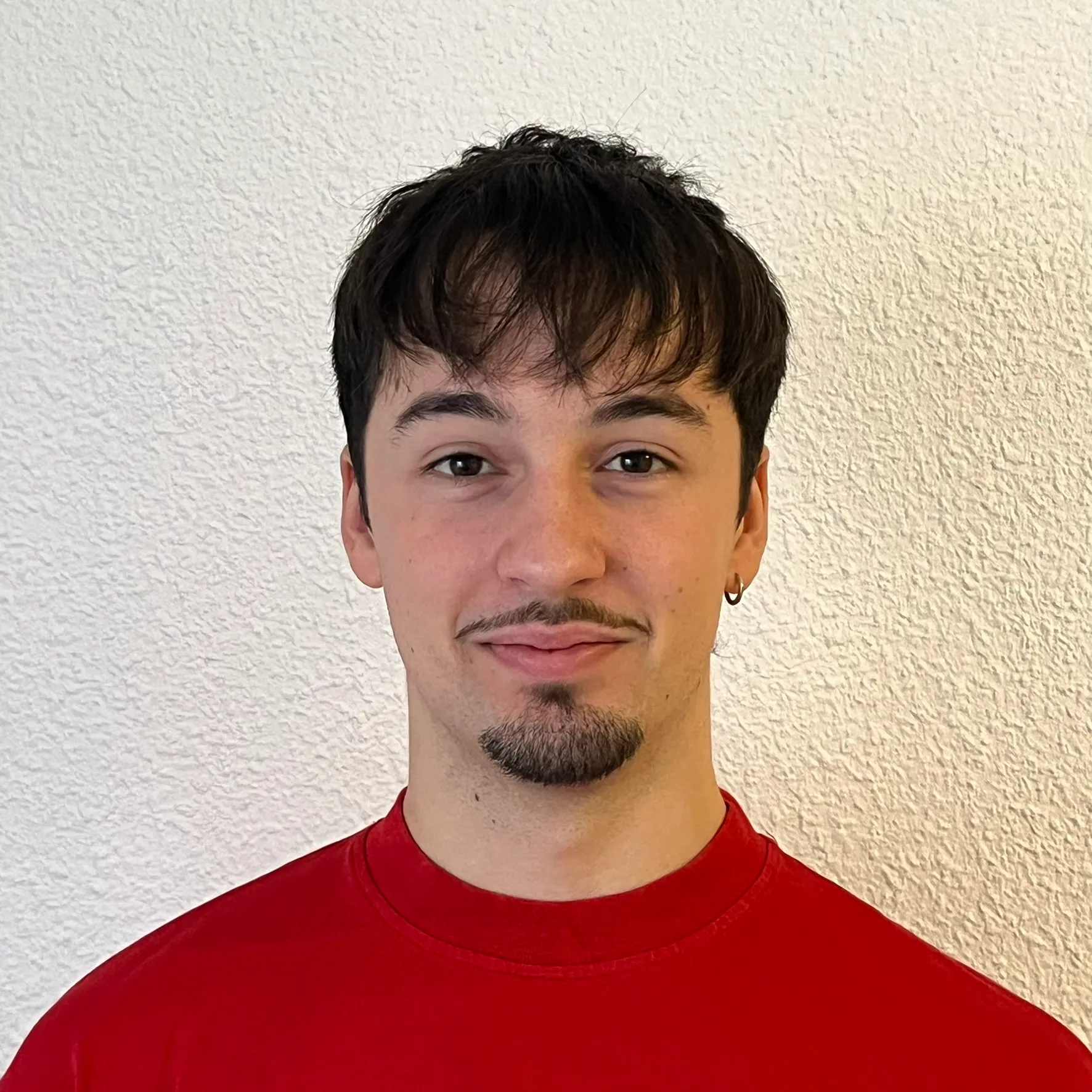 Alejo Arenas smiling in a red plaid shirt